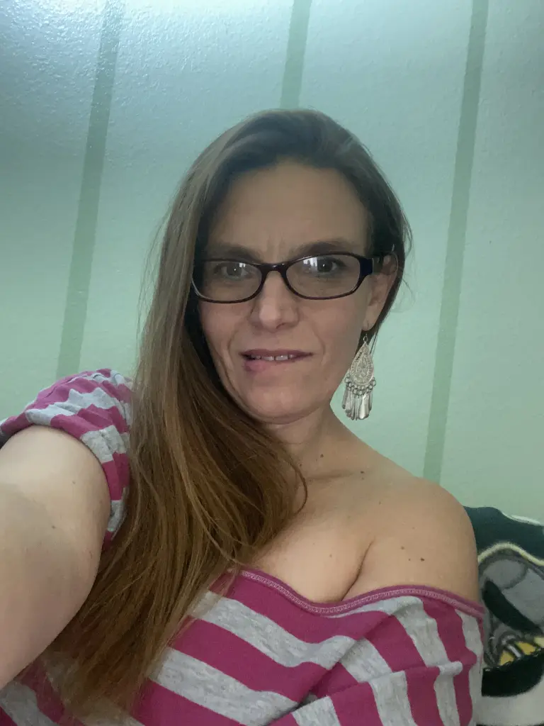 GeminiLoveXO has long brown hair and a direct gaze, posing close-up in a car setting.