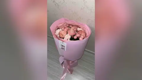 Elegant bouquet of pink peonies and white carnations wrapped in soft pink paper for a romantic gift.