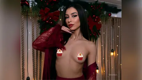 Young woman in a burgundy lace robe posing in a festive holiday setting with Christmas decorations.