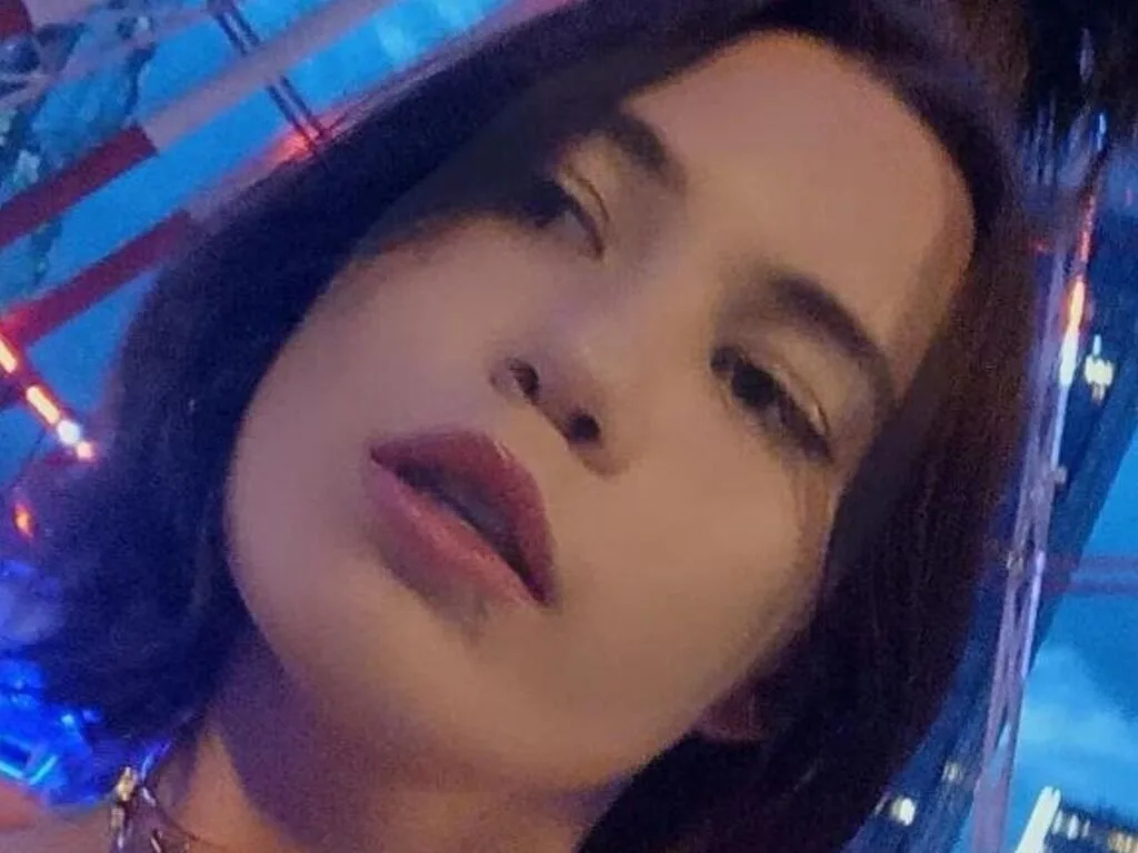 EdenHoon poses for a close-up selfie with dark hair and pink lips under blue lighting.