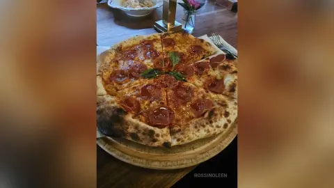Freshly baked pepperoni pizza with melted cheese on a wooden board in a cozy restaurant setting.
