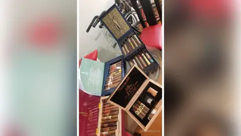 Luxury wooden cigar humidors and premium cigar boxes displayed on a glass table in a sophisticated setting.