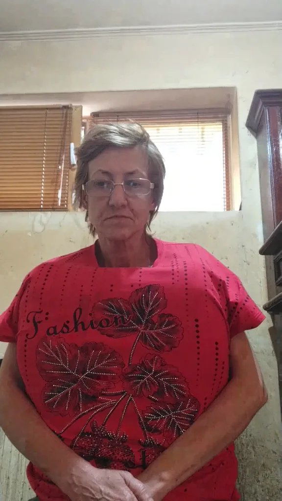 yougeny wears a red t-shirt with a black leaf pattern and glasses while looking directly at the camera.