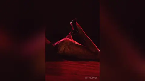 Moody red lighting illuminates a person reclining in black high heels for a dramatic, cinematic aesthetic.