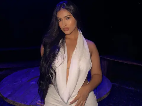 Young woman in a white halter neck outfit posing outdoors at night under moody blue lighting.