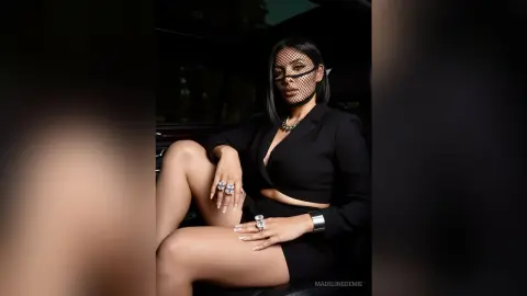 Elegant woman in a black blazer and veil sitting in a car with a sophisticated, moody aesthetic.