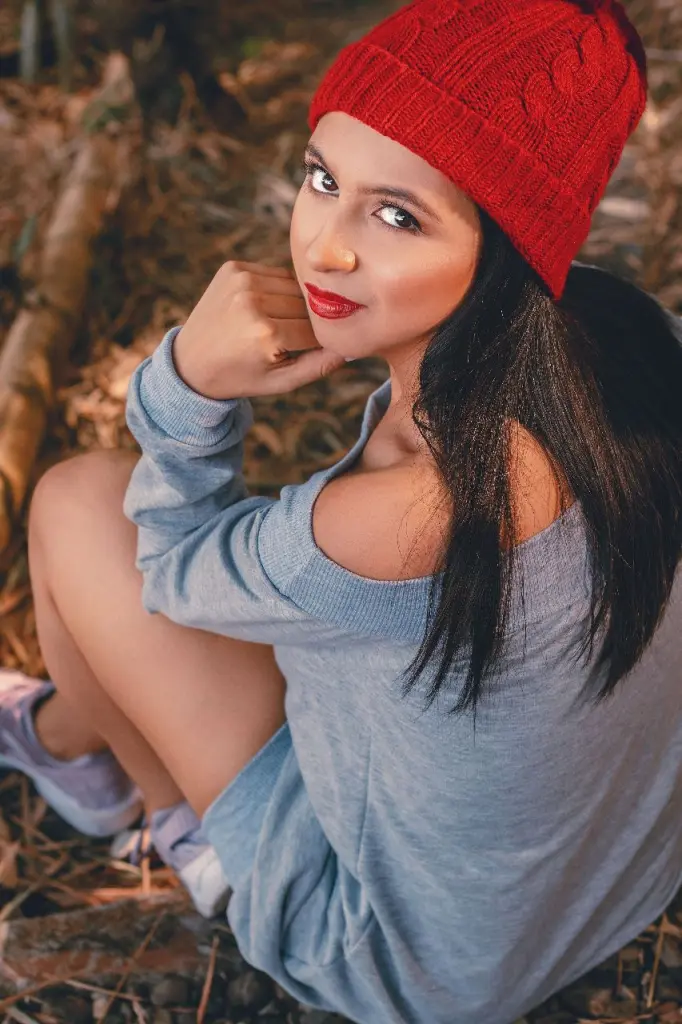 KassandraWood poses with long dark hair and red lipstick, looking directly at the camera in a close-up shot.