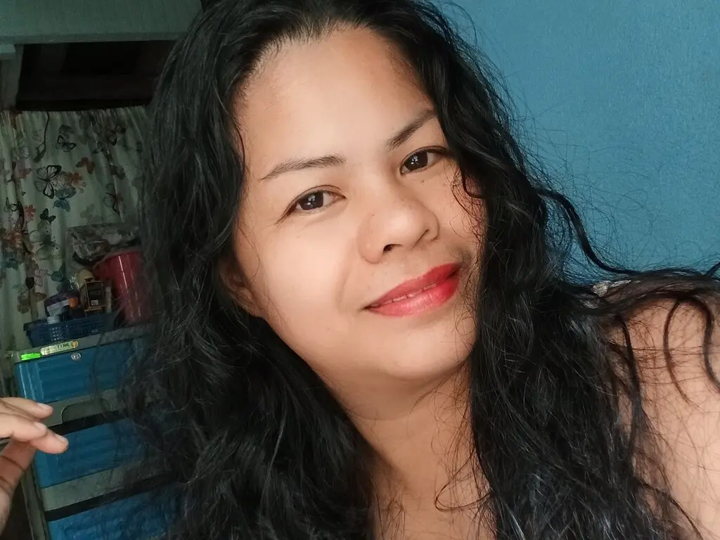 KathieBrown smiles with long, wavy black hair against a blue wall background.