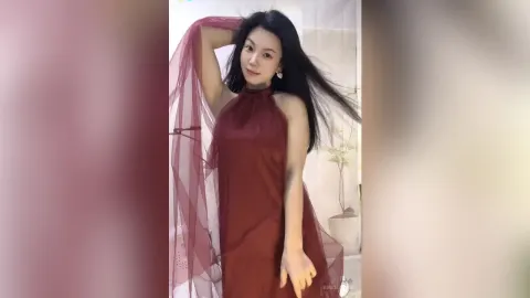 KireliaYan — KireliaYan poses in a flowing red halter dress with her long black hair blowing as she smiles.
