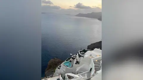 Serene view of a luxury white villa with a private pool overlooking the deep blue sea in Santorini at dusk.