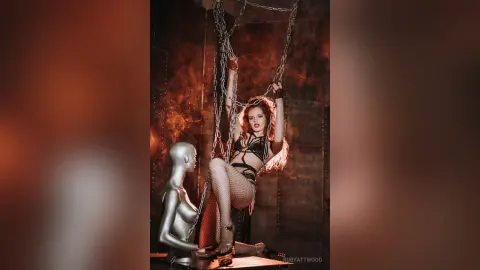 RubyAttwood poses in black strappy lingerie and fishnet stockings while hanging from metal chains.