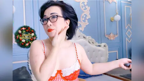Woman in red and white checkered lingerie posing in a blue classical style bedroom.