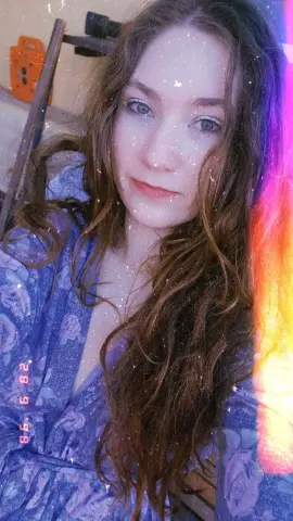jenellehayesxoxo poses with long wavy brown hair wearing a blue floral robe.