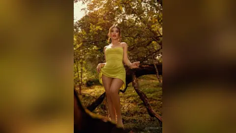 Elegant woman in a lime green mini dress standing in a sunlit forest setting with a dreamy, warm mood.