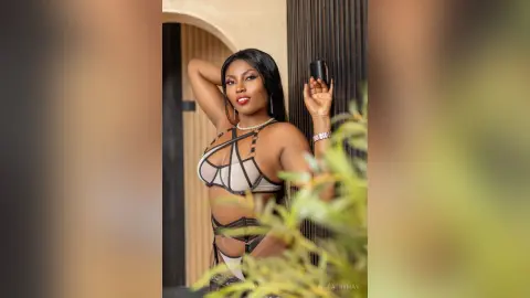 Glamorous Black woman in a stylish beige cutout bikini posing confidently in a sunlit outdoor setting.