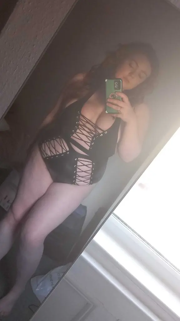 NaughtyNinaXX shows off her long dark hair and cleavage while wearing a black top in a close-up shot.