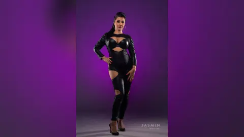 MissyJolie poses in a black cutout bodysuit and black high heels against a purple background.