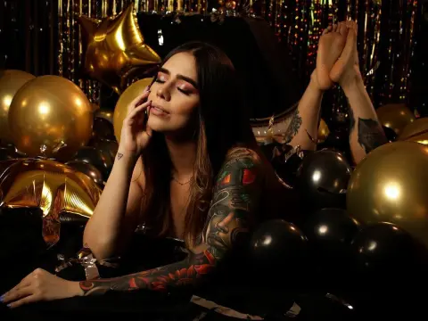 Nomohah_sainz poses with her legs raised in the air, surrounded by gold and black balloons against a shiny gold tinsel background.