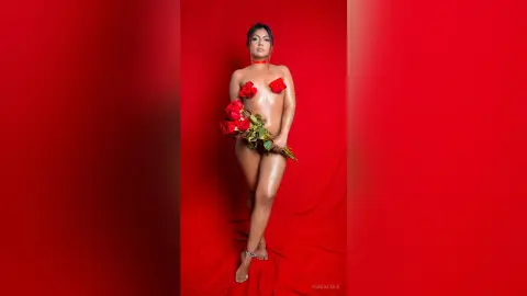 Glamorous woman in red rose bra holding a bouquet against a vibrant red background for a romantic photoshoot.