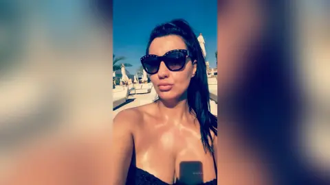 MissyJolie poses outdoors in black sunglasses and a black bra, showing off her wet, glowing skin under the sun.