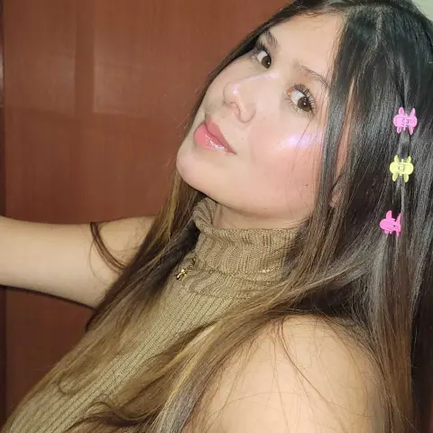 Young woman with long brown hair and cute hair clips wearing a beige ribbed turtleneck sweater.