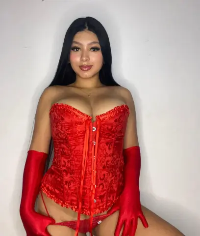 Young woman in a glamorous red lace corset and matching opera gloves posing against a white background.