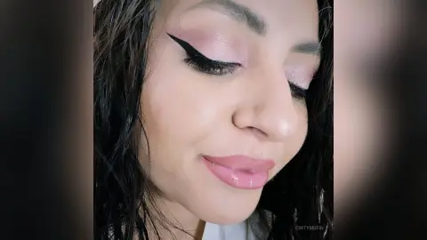 Close-up of a woman with pink eyeshadow and winged eyeliner featuring a soft, glamorous makeup look.