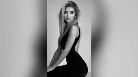 Elegant woman in a sleek black evening gown posing with a sophisticated mood in a studio setting.