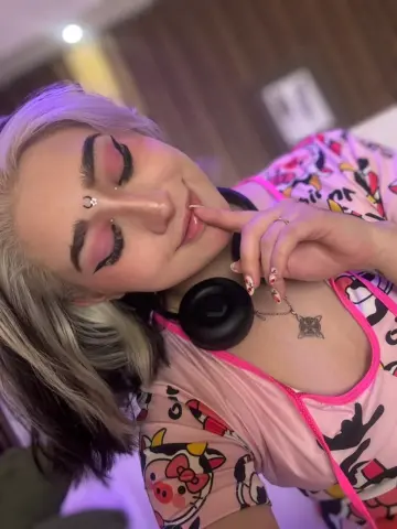 Young woman with blonde hair and pink patterned top relaxing in a cozy indoor setting.