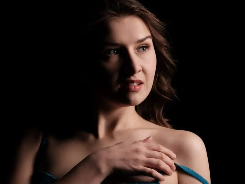 Portrait of a brunette woman posing with a thoughtful expression against a dark studio background.