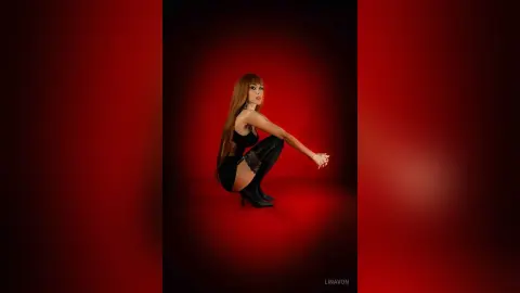 LinaVon poses in black lingerie and thigh-high stockings against a red background.