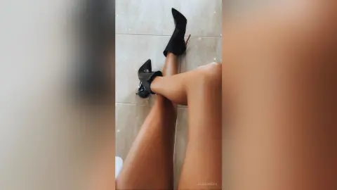 Close-up of legs wearing elegant black high heel stiletto boots on a marble floor.