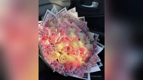 Beautiful bouquet of pink and peach roses with baby's breath in a gift wrap inside a car.