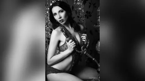 Elegant woman in lace lingerie posing in a moody, black and white setting with a decorative hookah.