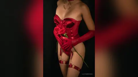 Woman in glamorous red satin corset and matching gloves posing in a moody, dramatic red studio setting.