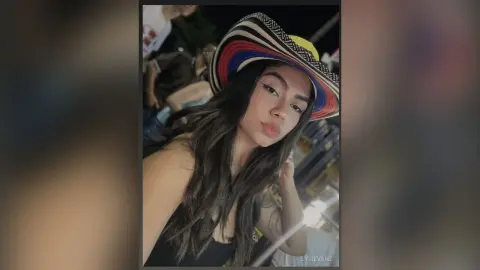 Young woman in a colorful striped sun hat smiling during a summer evening outdoors.