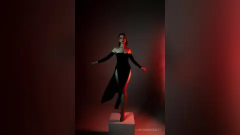 Elegant woman in a black evening gown posing dramatically in a moody, red-lit studio setting.