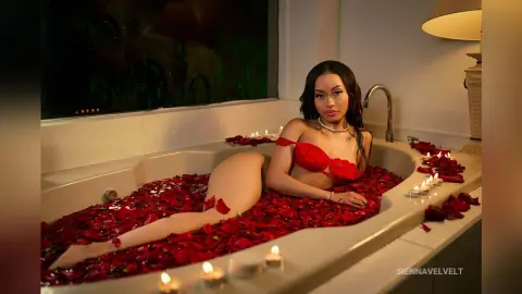 Glamorous woman in red lingerie relaxing in a luxury bathtub filled with red rose petals.