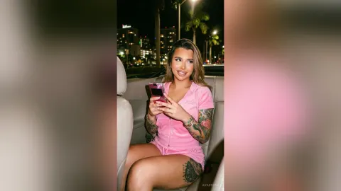 AvaBronX — AvaBronX sits in a car at night wearing a pink ribbed outfit and showing off her colorful arm tattoos.