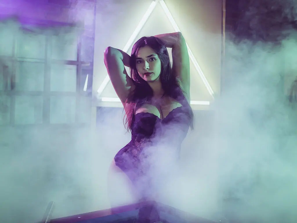 Mysterious woman in a black lace outfit posing amidst dreamy purple fog and neon lighting.
