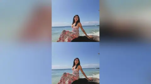 Serene woman in a floral maxi dress sitting on coastal rocks by the blue ocean under a clear sky.