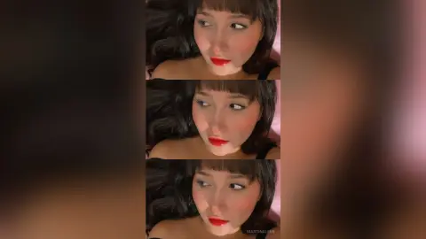 Young woman with dark hair and red lipstick posing in a moody, close-up portrait.