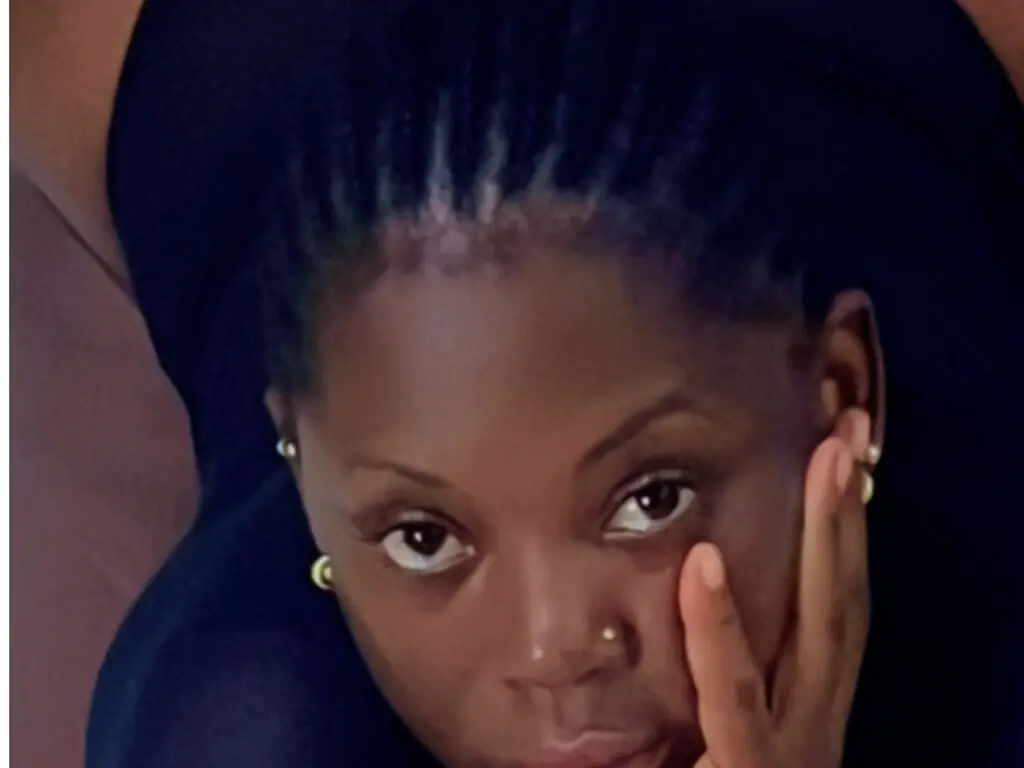 Close-up portrait of a beautiful Black woman with braided hair posing with a thoughtful expression indoors.
