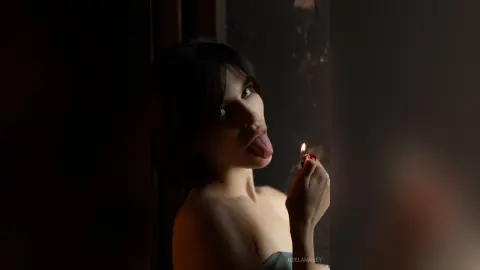 Moody portrait of a woman in a dark setting lighting a candle with a romantic, cinematic atmosphere.
