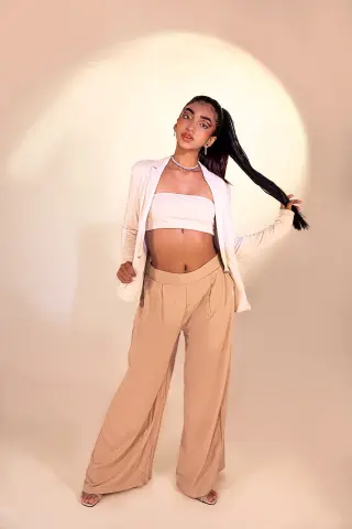 Veronica_Hottiee poses in a white tube top and tan wide-leg trousers with a matching white blazer.