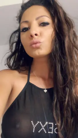 Brunette woman in a black halter top making a playful kissy face in a casual indoor setting.