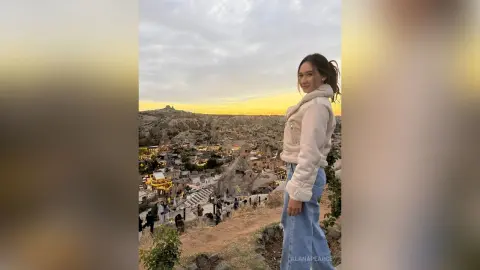 AlanaPearce poses outdoors at sunset, wearing a white fleece jacket and blue jeans with her hair tied back in a ponytail.