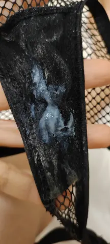 Close-up of white discharge on black fishnet fabric texture.