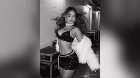 Glamorous woman in a black sequin bikini and white faux fur coat posing in a studio setting.