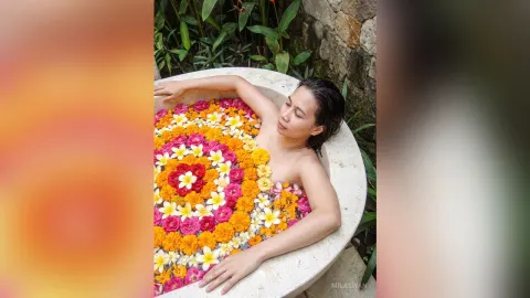 MilaSwan — MilaSwan relaxes in a stone bathtub filled with colorful pink, orange, and yellow flowers.